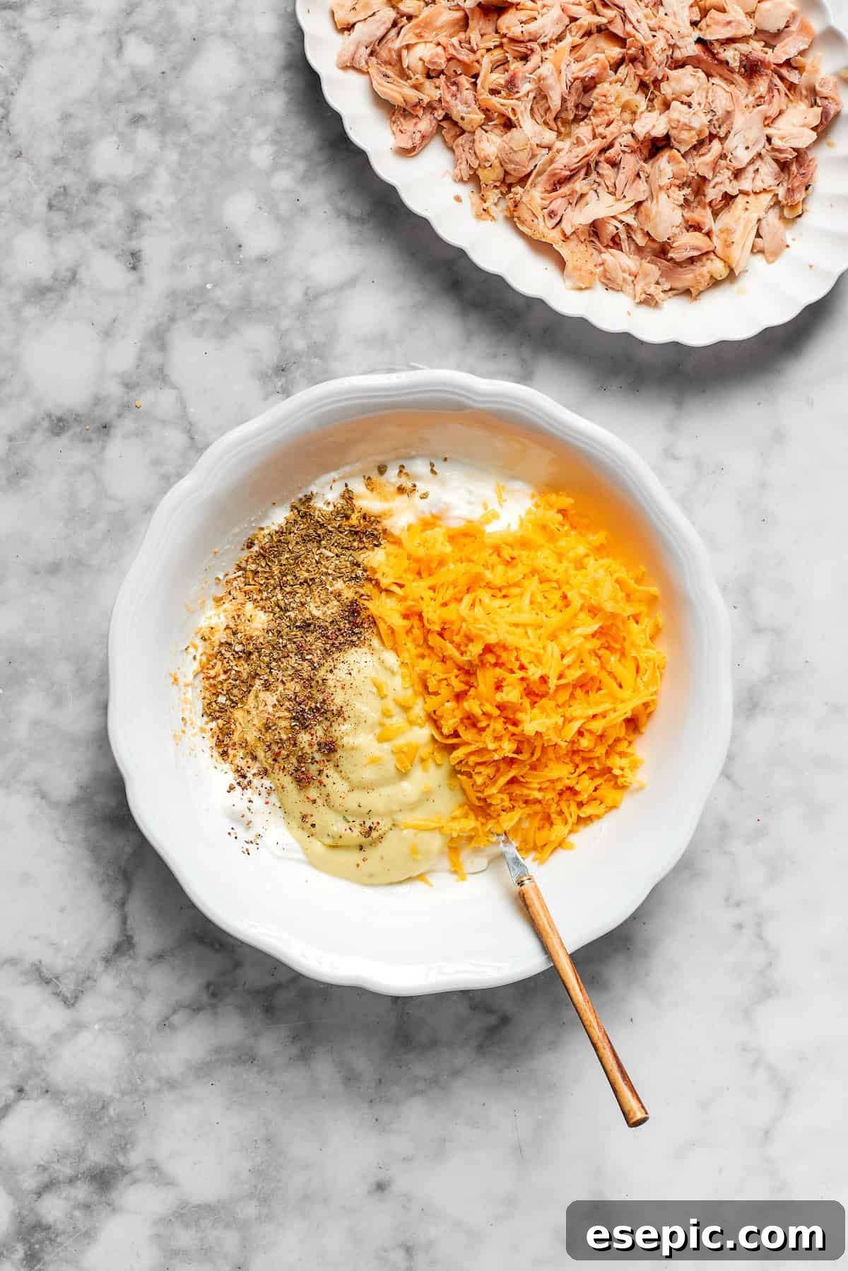 Cheese, condensed soup, and seasonings being mixed together in a bowl for the casserole filling.