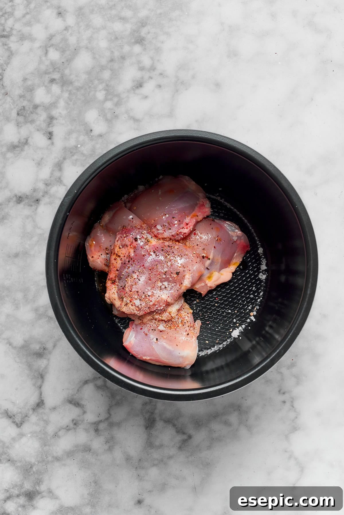 Chicken thighs cooking in an Instant Pot with onions, garlic, and broth.