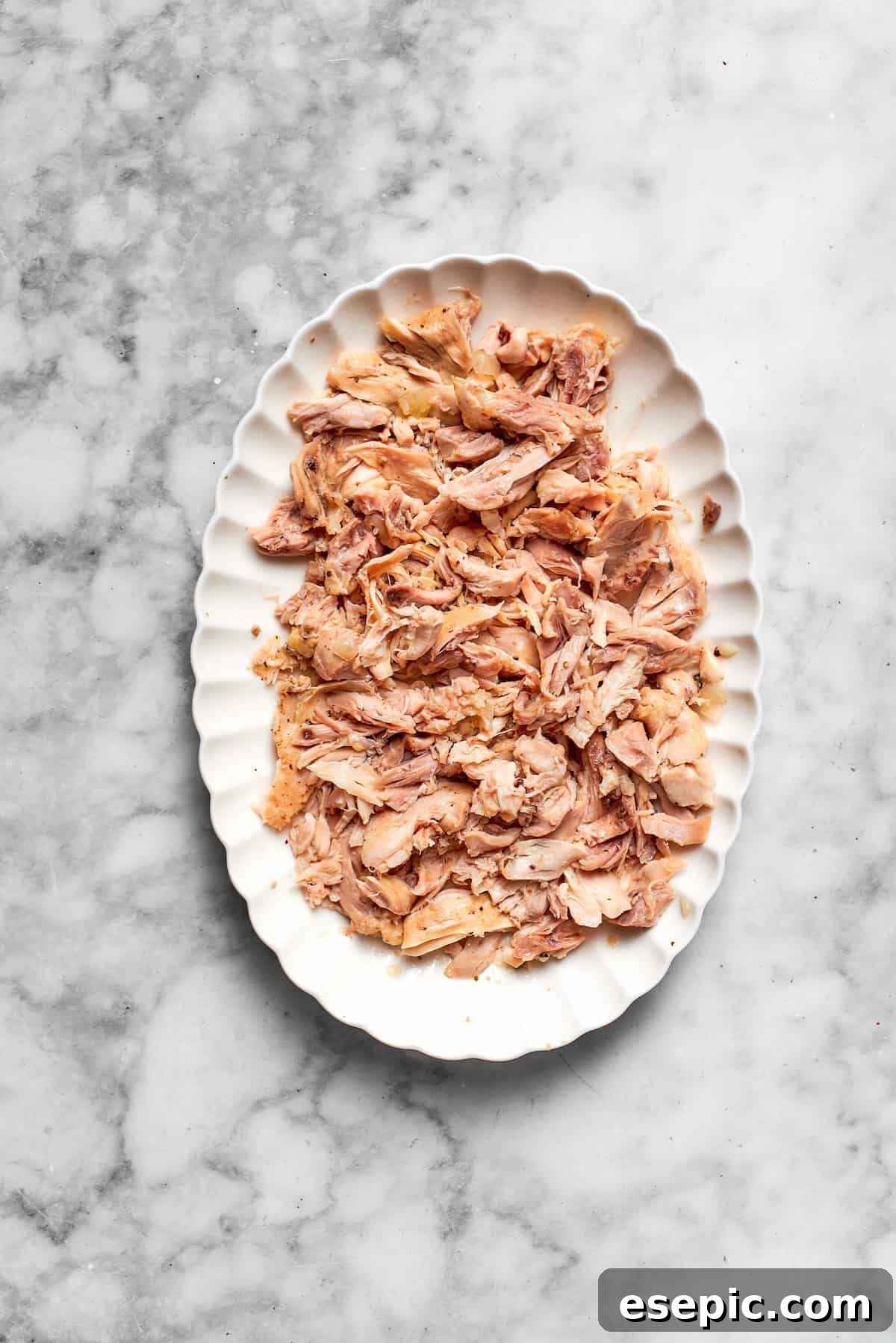 Freshly shredded chicken on a cutting board, ready for the casserole.