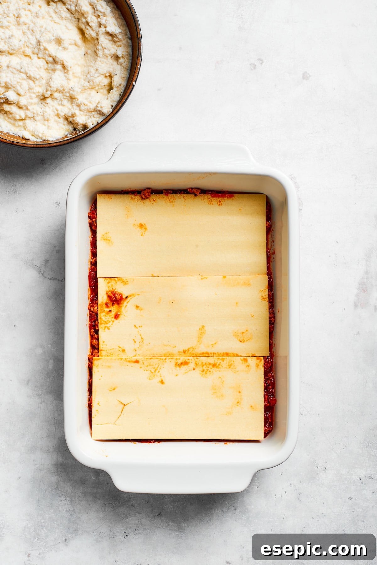The best beef lasagna recipe is packed with tons of meaty, cheesy flavor and a rich and savory sauce. Make ahead friendly! Cooked lasagna sheets carefully layered over a bed of meat sauce in a baking pan.