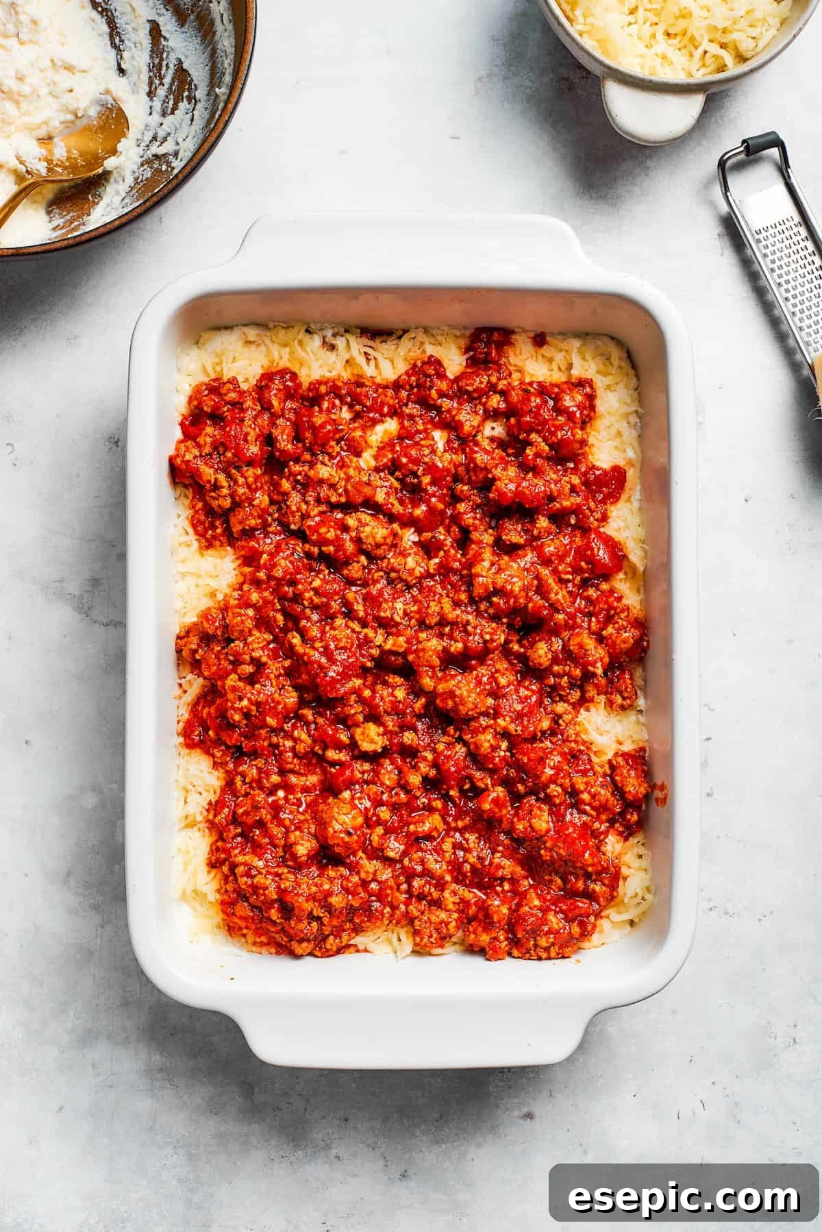 The best beef lasagna recipe is packed with tons of meaty, cheesy flavor and a rich and savory sauce. Make ahead friendly! Rich meat sauce being carefully spooned over a cheesy layer in a developing beef lasagna.