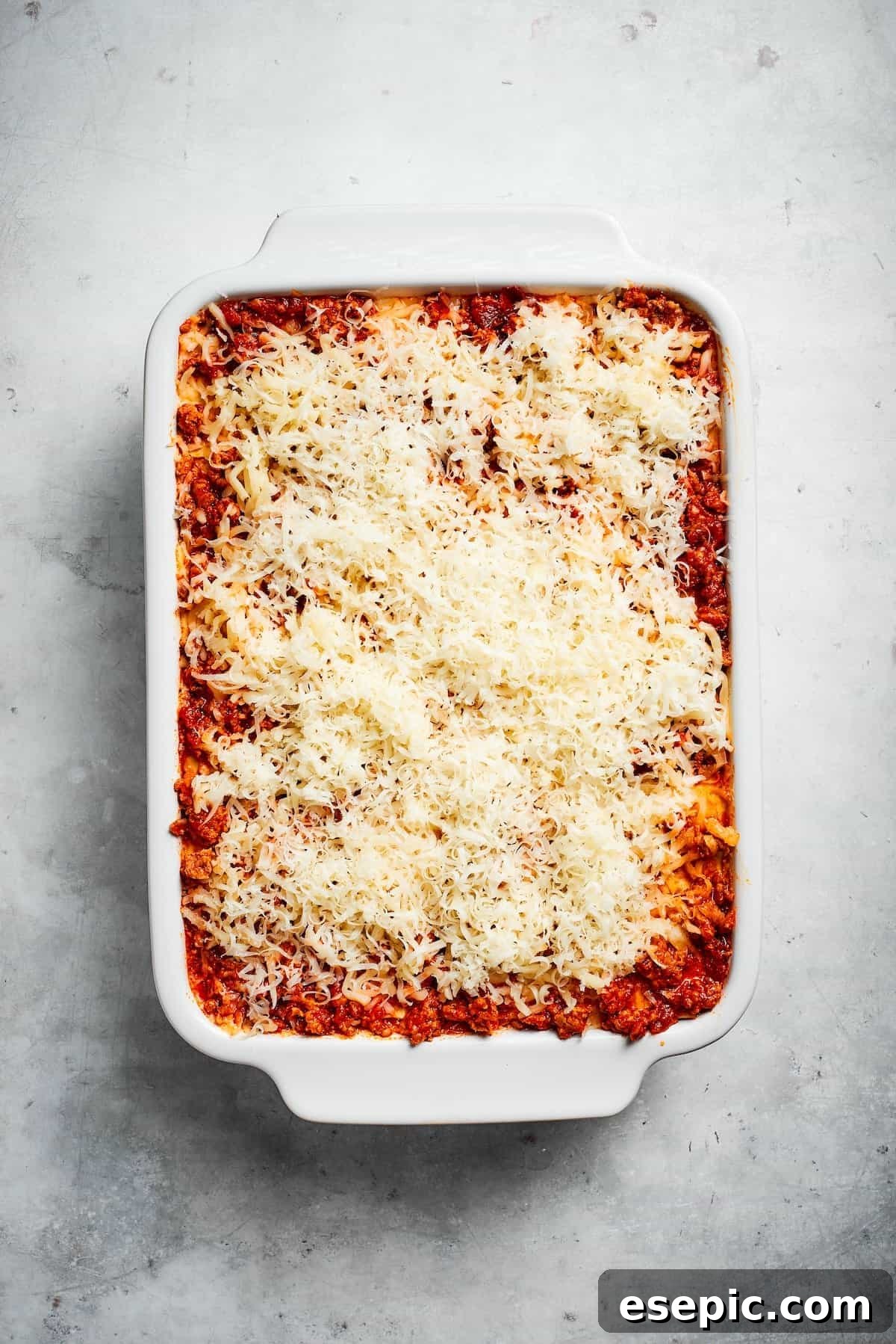 The best beef lasagna recipe is packed with tons of meaty, cheesy flavor and a rich and savory sauce. Make ahead friendly! A finished, unbaked pan of beef lasagna, generously topped with a final layer of shredded cheese.