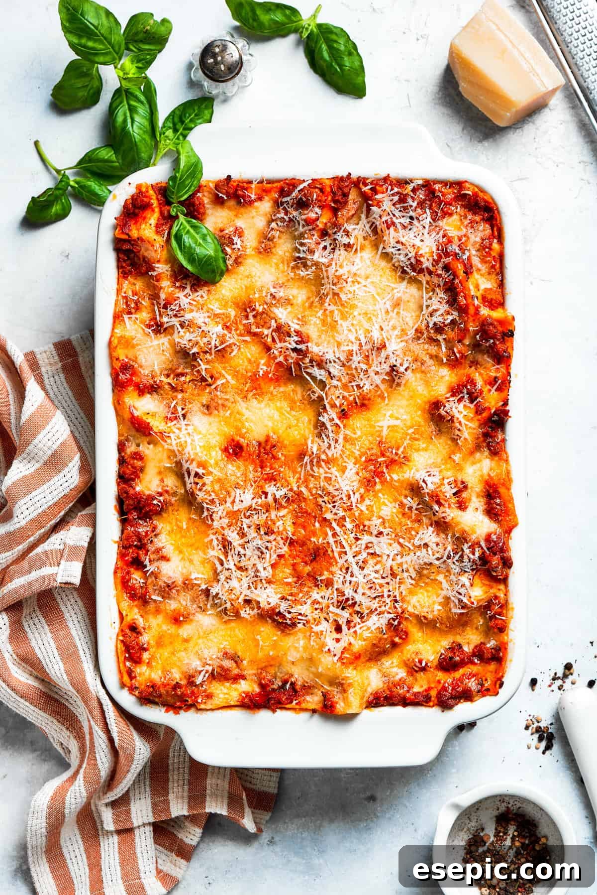 The best beef lasagna recipe is packed with tons of meaty, cheesy flavor and a rich and savory sauce. Make ahead friendly! An overhead shot of a freshly baked beef lasagna in a white ceramic baking dish, golden and bubbly.