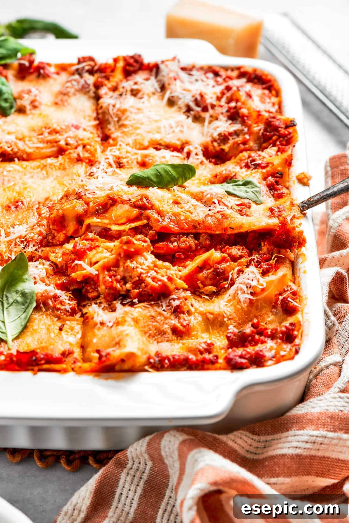 The best beef lasagna recipe is packed with tons of meaty, cheesy flavor and a rich and savory sauce. Make ahead friendly! Lifting out a perfectly baked slice of lasagna from a baking dish, revealing its distinct layers.