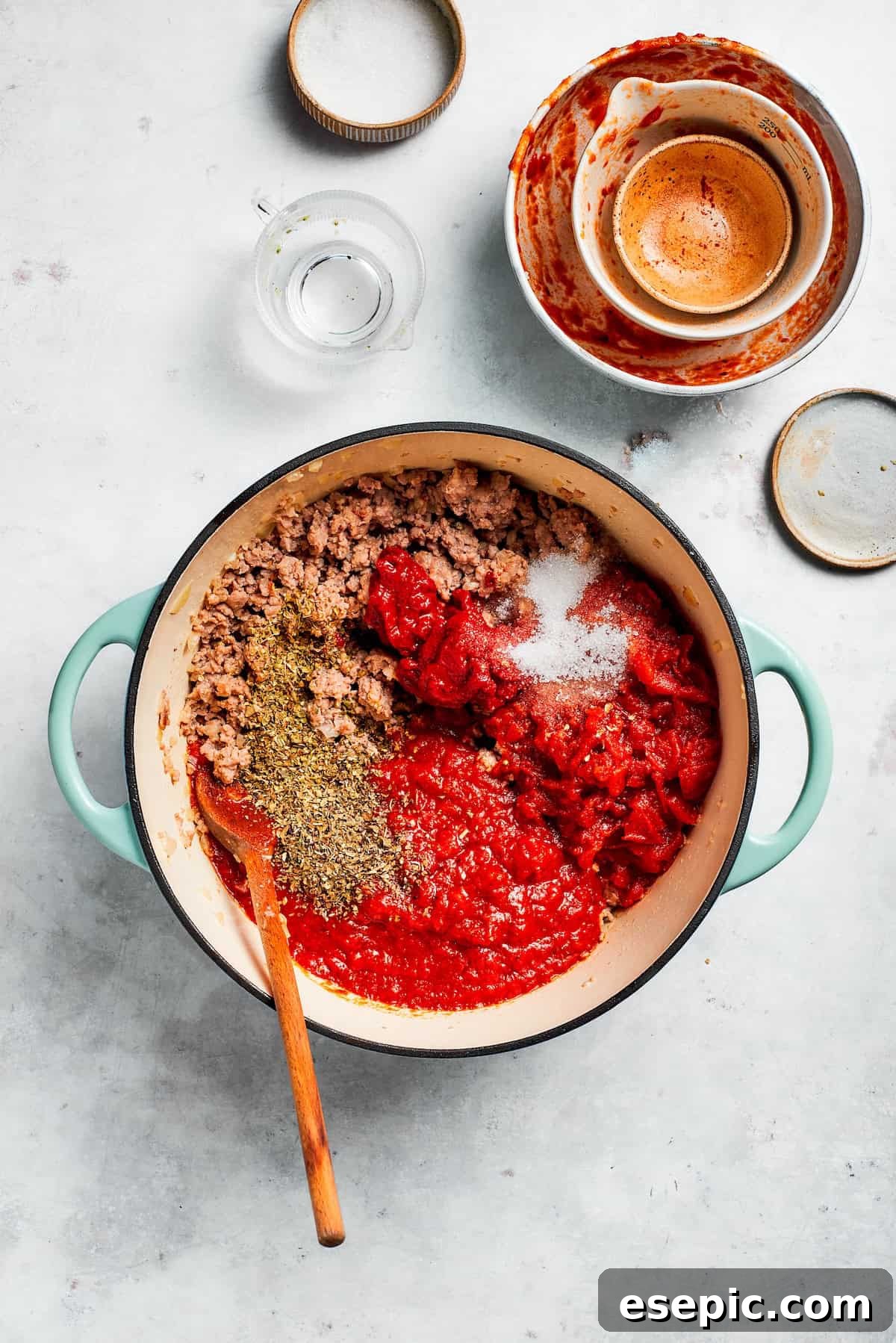 The best beef lasagna recipe is packed with tons of meaty, cheesy flavor and a rich and savory sauce. Make ahead friendly! Crushed tomatoes, tomato paste, and tomato sauce being added to the browned beef and aromatics in a skillet.