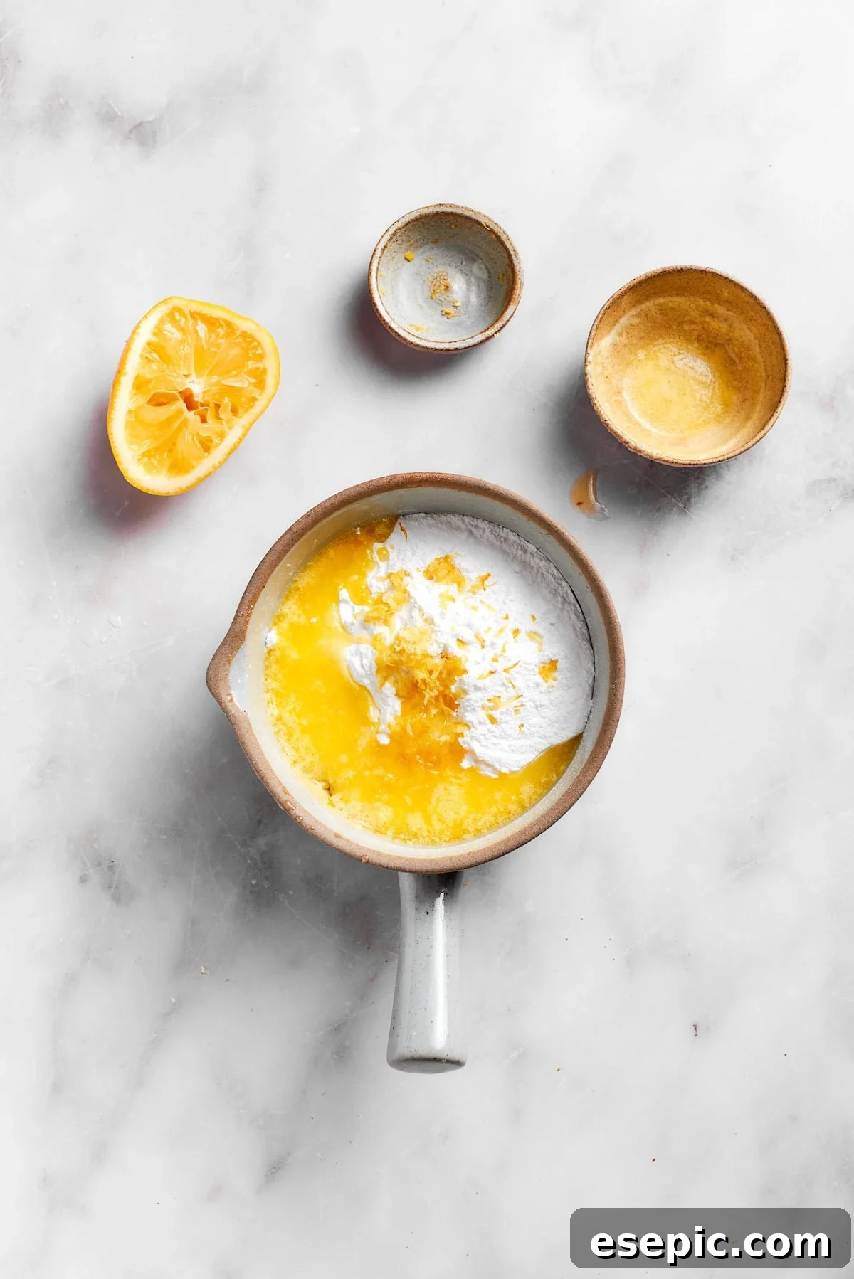 Ingredients for the lemon slice frosting, including powdered sugar, lemon juice, melted butter, and lemon zest, being combined in a bowl.