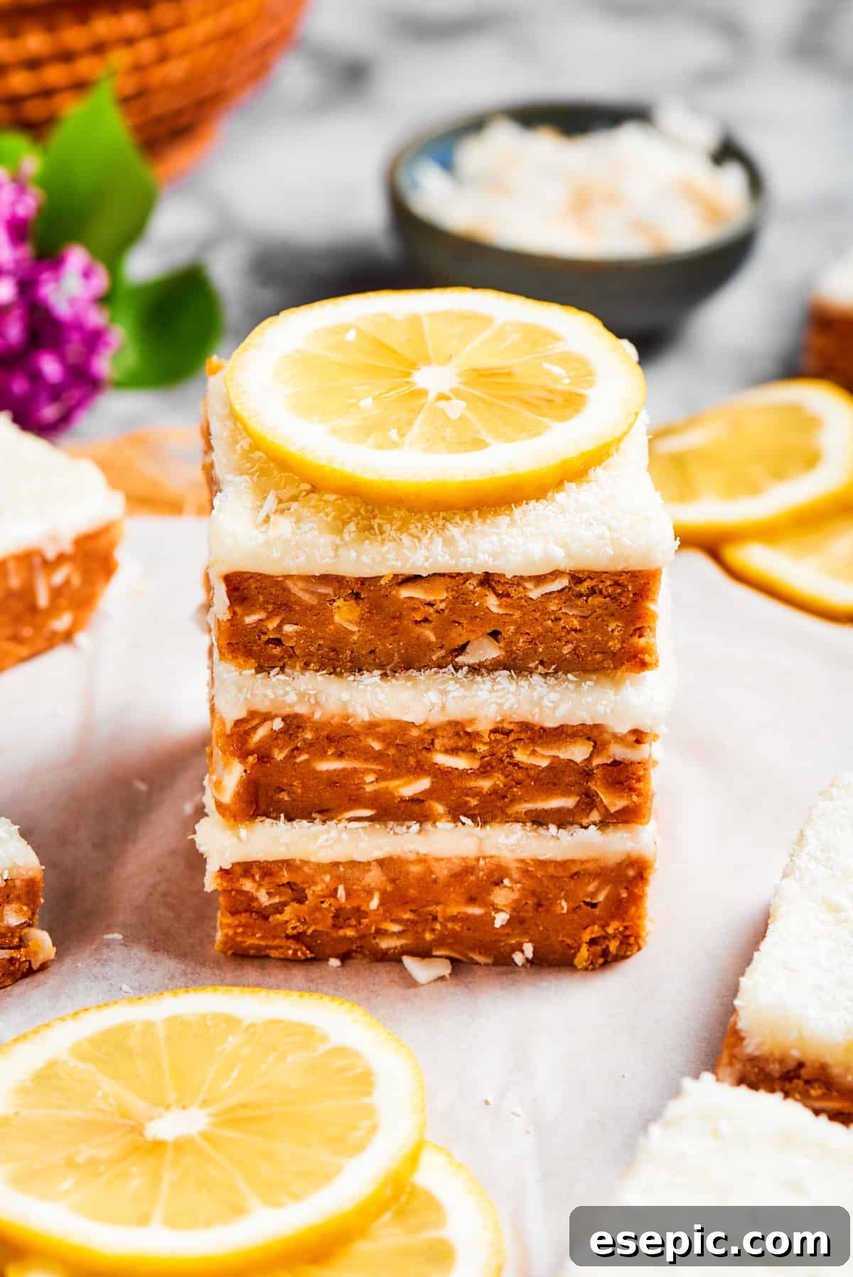 A stack of three lemon slice squares, perfectly garnished with a thin slice of lemon, highlighting the vibrant yellow frosting.