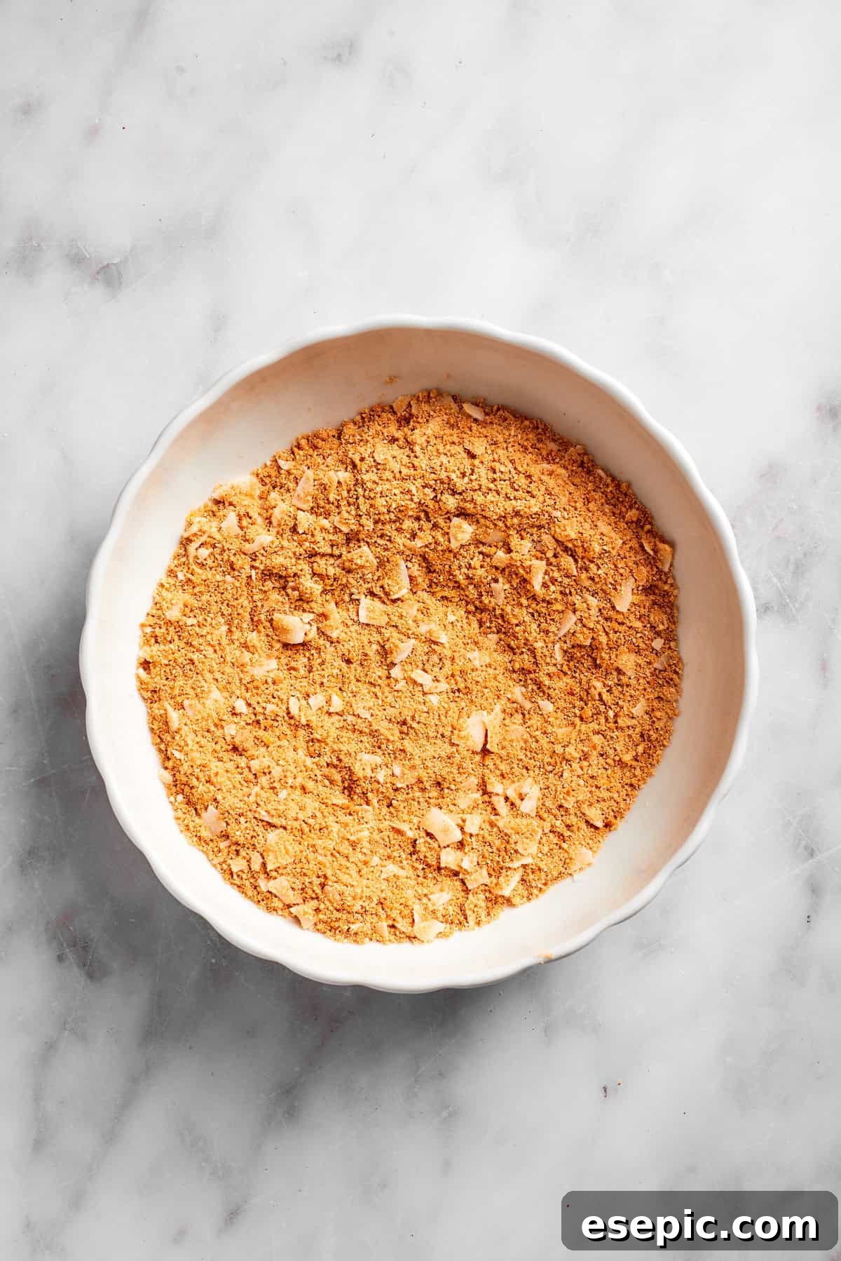 The graham cracker, coconut, and lemon zest mixture thoroughly combined in a mixing bowl, showing a uniform texture.