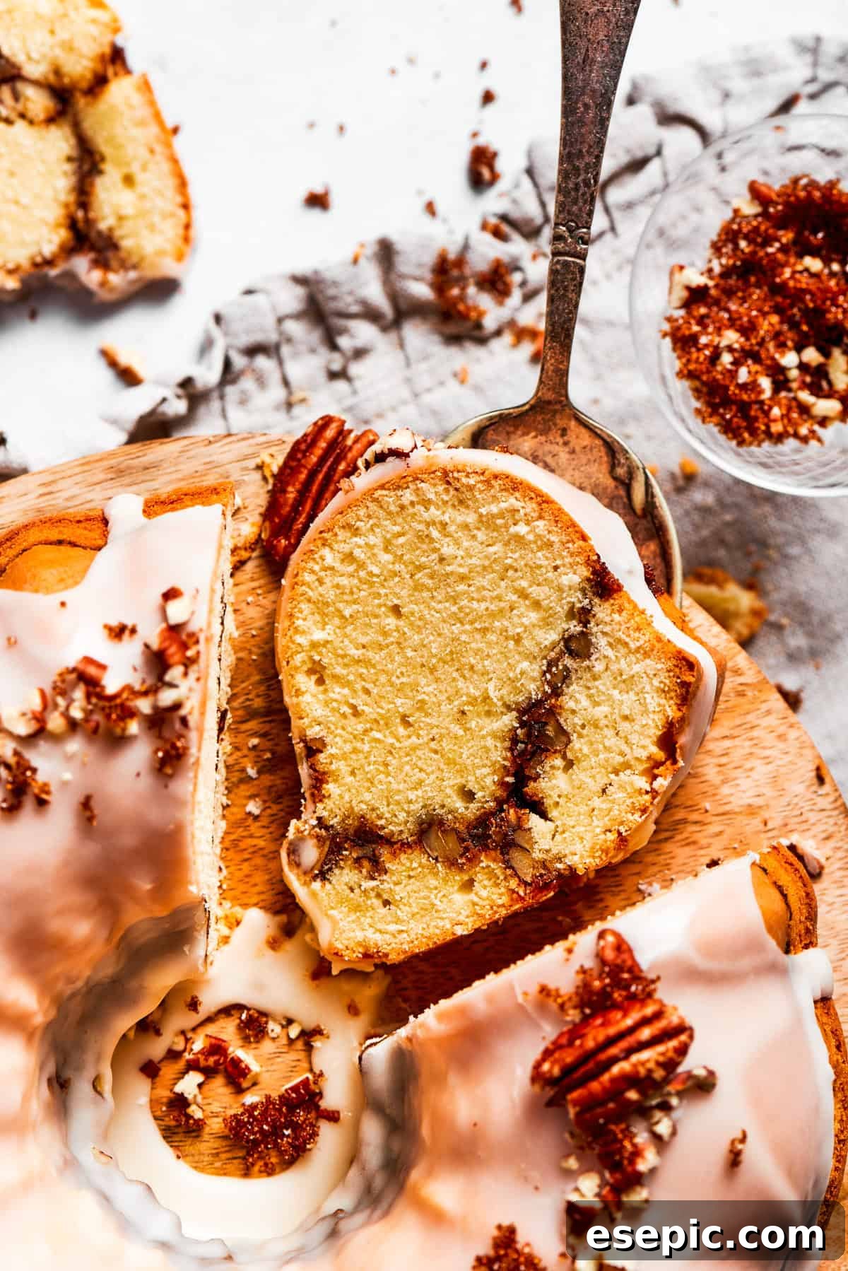 A slice of sock it to me cake on a white plate with the cinnamon sugar ribbon visible across it, drizzled with vanilla glaze.