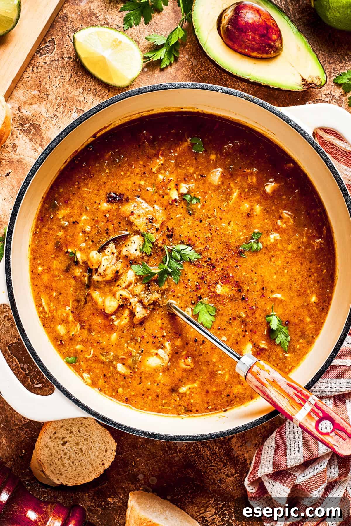 A large pot brimming with spicy chicken soup, stirred to perfectly combine all the vibrant ingredients, showcasing tender chicken and beans.