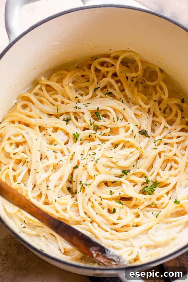 Top shot of cream cheese spaghetti in a white pot, ready to be served, with a spoon for scooping