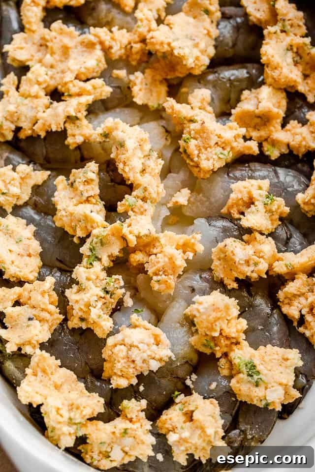 top view of raw shrimp with dollops of butter on top of them.