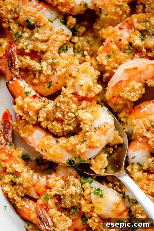 Scooping out Garlic Butter Baked Shrimp with silver spoon.