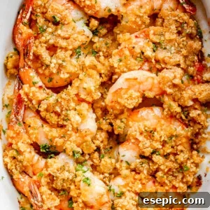 overhead shot of arranged shrimp in a white oval dish and topped with garlic butter and breadcrumbs mixture
