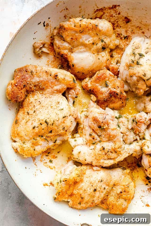 Boneless, skinless chicken thighs seasoned and ready to be cooked in a white skillet.