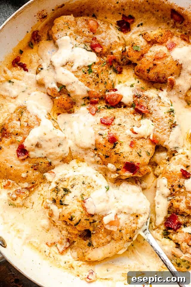 Close-up of perfectly cooked cream sauce chicken thighs in a white skillet, garnished and ready to serve.