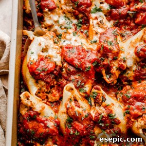close up top view of pasta shells stuffed with beef and topped with shredded cheese and marinara