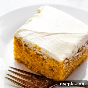 side shot of frosted pumpkin bar on a plate with a fork next to it