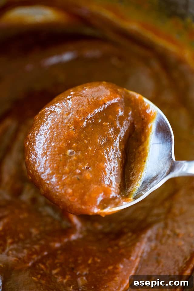 Velvety Smooth Instant Pot Apple Butter 7 Overhead shot of rich, dark apple butter on a spoon, ready to be enjoyed