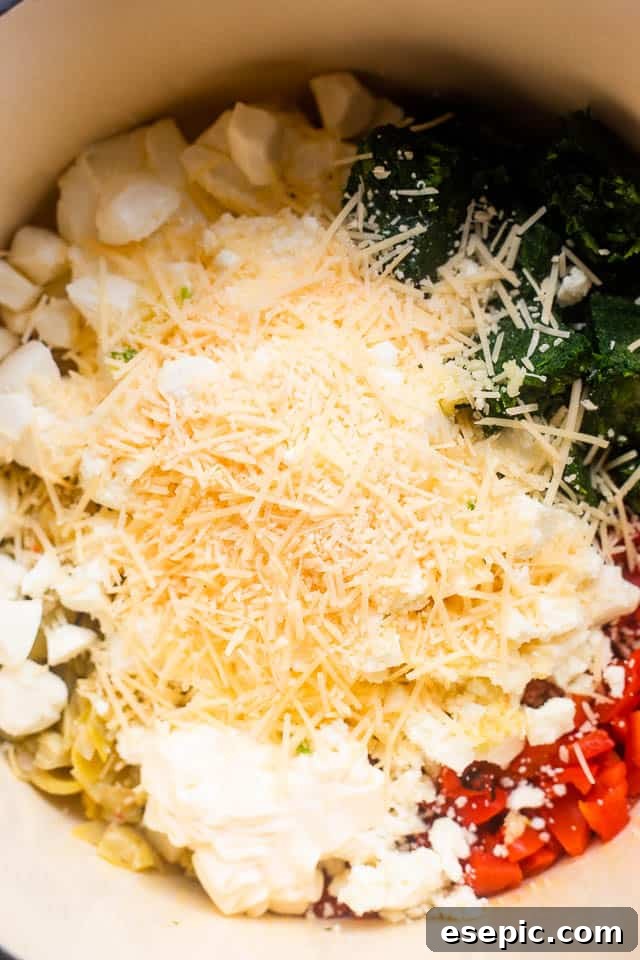 Overhead shot of all ingredients for slow cooker spinach artichoke dip assembled in a slow cooker before cooking.