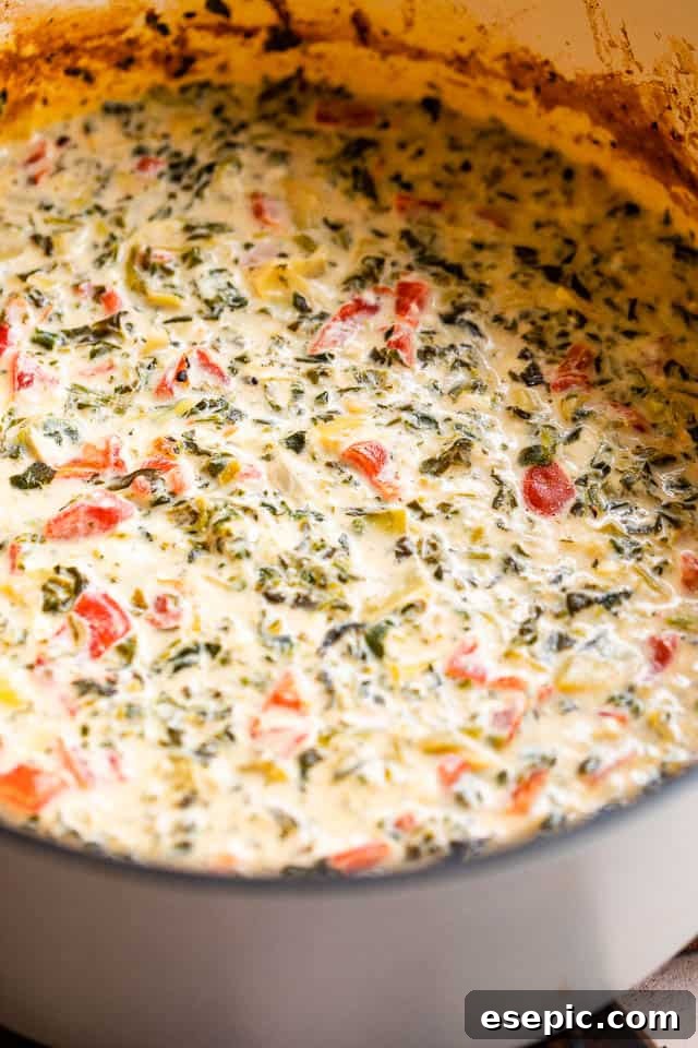 Side shot of the bubbling slow cooker spinach artichoke dip, freshly cooked and ready to serve.