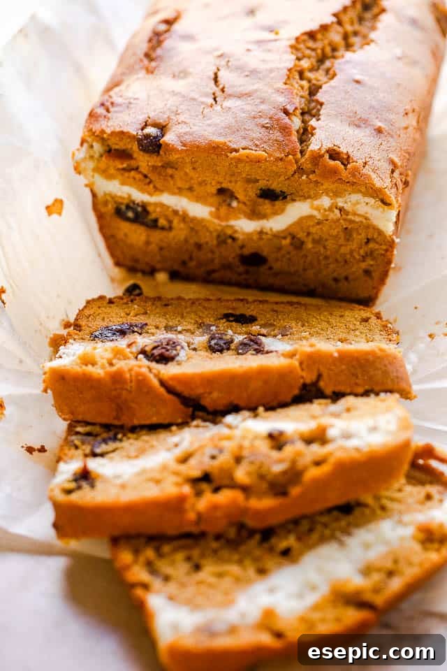 A perfectly sliced loaf of Pumpkin Swirl Bread, revealing its golden-orange pumpkin base and a delightful white cream cheese swirl, ready to be enjoyed.