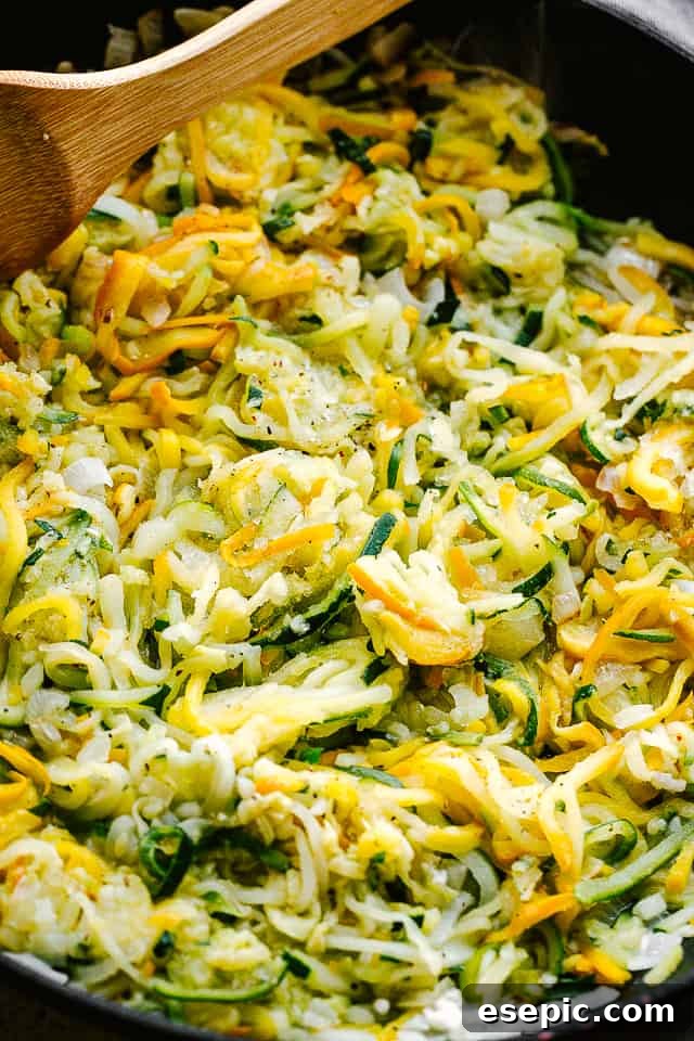 Golden Zucchini Squash Gratin 3 Close-up shot of spiralized zucchini being sautéed in a black frying pan with olive oil