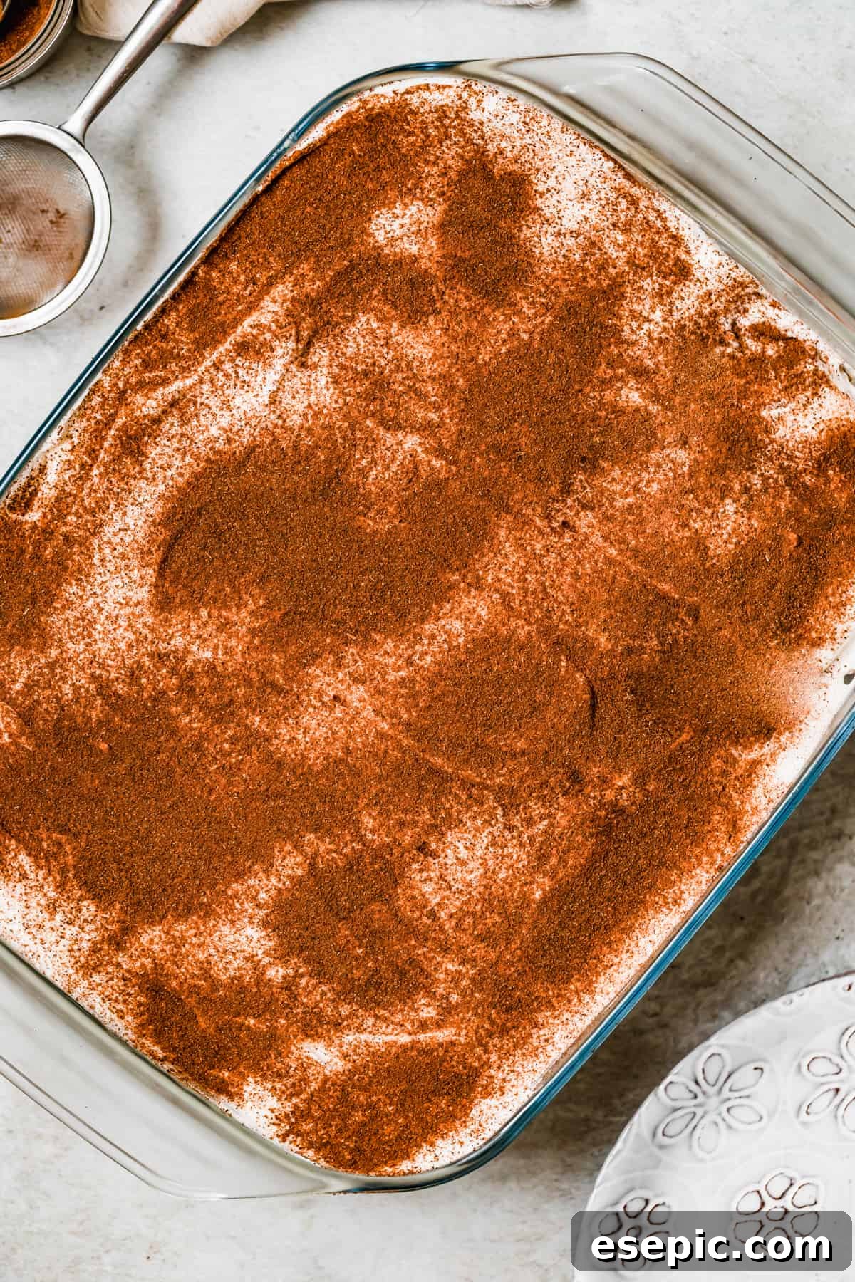 Effortless Three Milk Delight 2 A beautifully prepared Tres Leches Cake in a baking pan, topped with cinnamon and ready to be served.