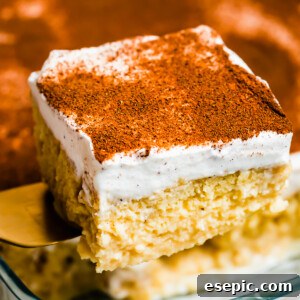 Effortless Three Milk Delight 3 Lifting out a piece of tres leches cake from a glass baking dish.