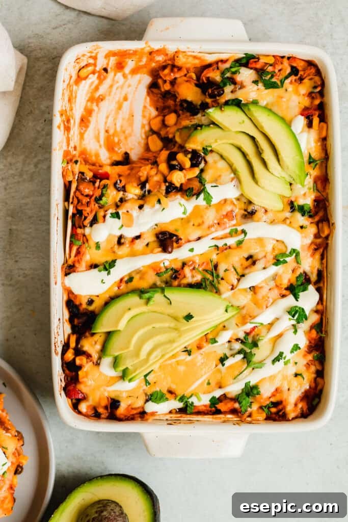 A hot chicken enchilada casserole in a baking dish, served alongside fresh avocado slices and a clean white plate, ready for serving.