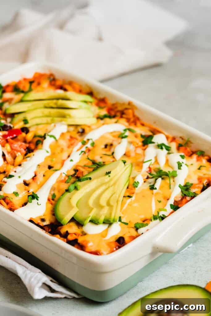 A freshly baked enchilada casserole generously topped with creamy sour cream and vibrant avocado slices, ready to be enjoyed.