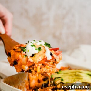 A serving of homemade Chicken Enchilada Casserole on a large wooden scoop, garnished with fresh herbs.