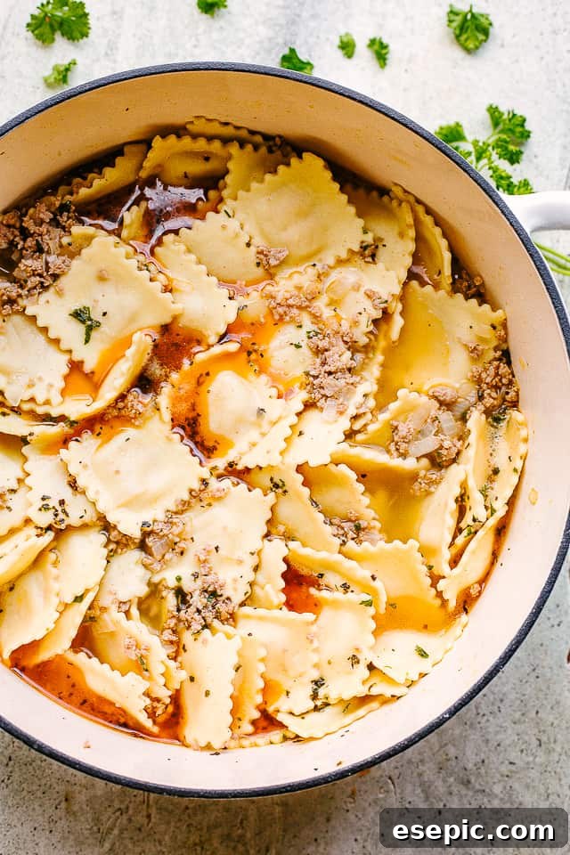 A large pot on the stovetop, with sautéed onions, carrots, and browned ground turkey, forming the aromatic base for the creamy ravioli soup.