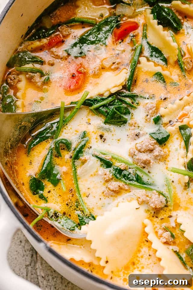 A close-up view of creamy ravioli soup, showcasing tender ravioli, vibrant green spinach, and the rich, creamy texture of the broth.