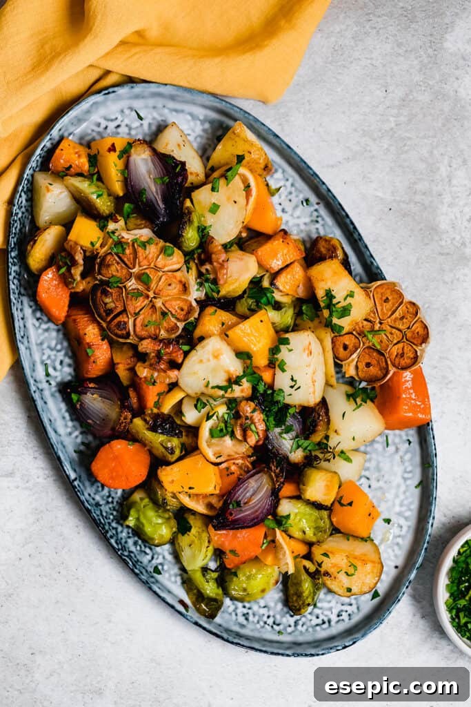 A vibrant medley of roasted root vegetables and Brussels sprouts served on an elegant blue platter, garnished with fresh herbs.