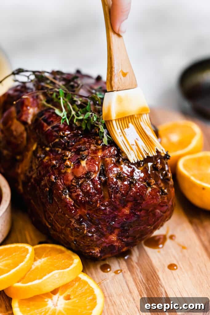 A Close-Up of the Glazed Christmas Ham, being topped with more glaze after cooking.