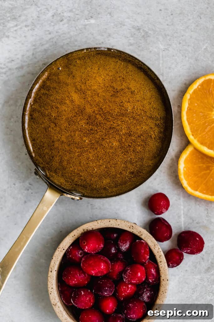 A saucepan filled with homemade brown sugar glaze, simmering gently, beside a bowl of fresh fruit.