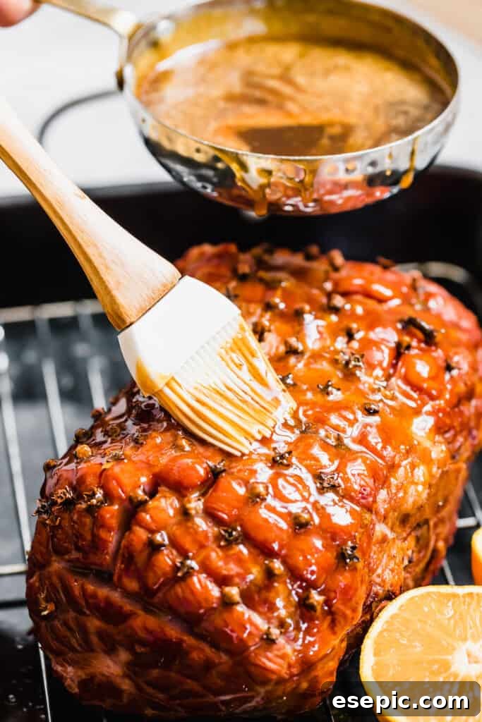 Brown Sugar Glaze being poured and brushed over a partially baked ham.