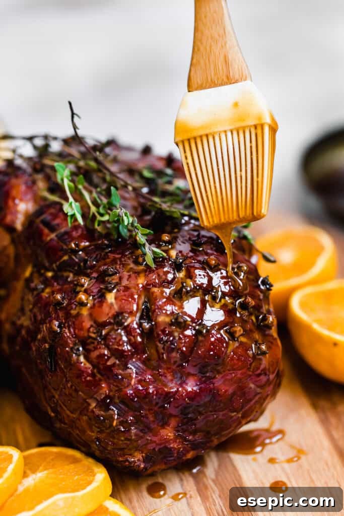 Brown sugar glaze being poured over a golden, fresh-from-the-oven ham.