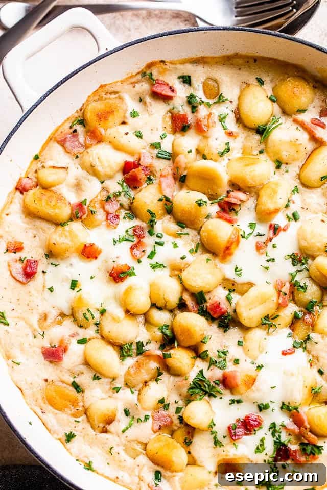 Golden Gnocchi and Crispy Bacon Bake 2 Overhead shot of a bubbling gnocchi and bacon casserole in a baking dish, garnished with fresh chives