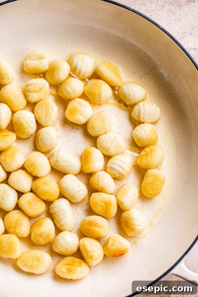Golden Gnocchi and Crispy Bacon Bake 4 Gnocchi being pan-fried in a white skillet, turning golden brown and crispy