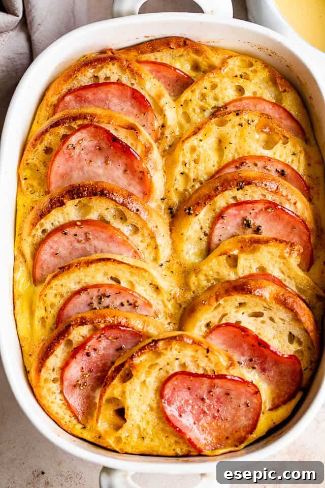 Overhead shot of golden brown Eggs Benedict Casserole in a white rectangular baking dish, fresh from the oven.