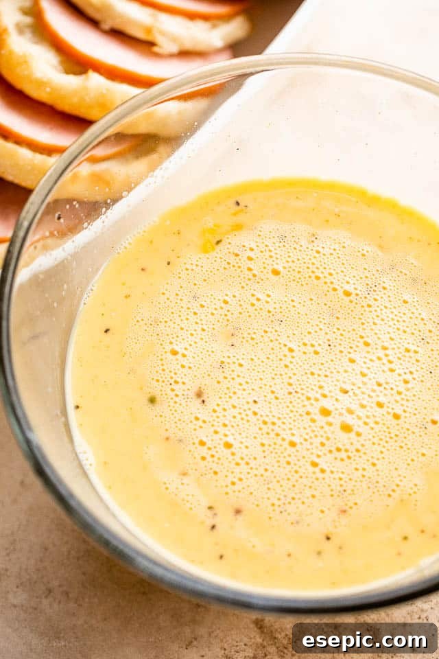 A large glass bowl containing whisked eggs and milk mixture, ready for the casserole.