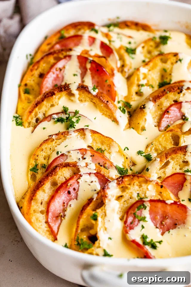 Overhead shot of the finished baked Eggs Benedict Casserole, beautifully golden, with a generous drizzle of Hollandaise sauce over the top.