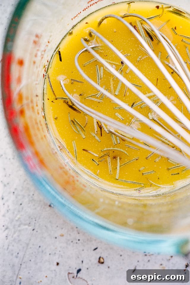 Whisking the Honey Garlic Butter Glaze Close-up shot of a glass cup with melted butter, minced garlic, and honey being whisked together, forming the flavorful glaze.