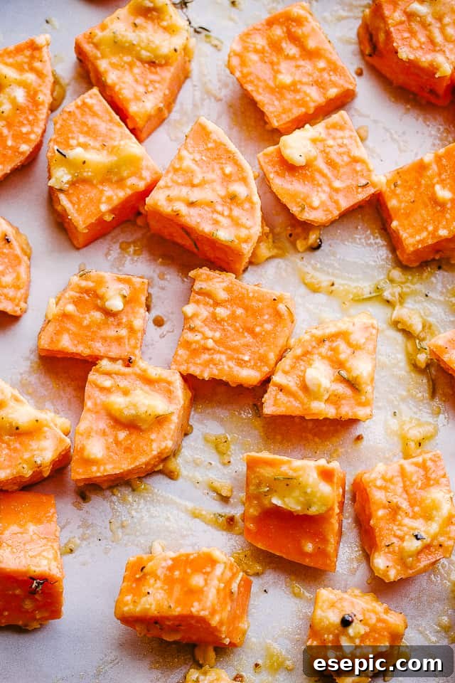 Sweet Potatoes on Baking Sheet Close-up overhead shot of diced sweet potatoes evenly spread on a parchment-lined baking sheet before roasting.