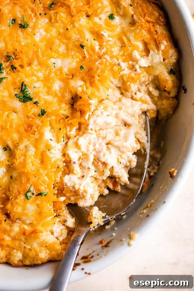 Creamy Baked Crab Dip 2 Close up shot of a spoon scooping into a golden, bubbly hot crab dip in a baking dish, garnished with fresh parsley.