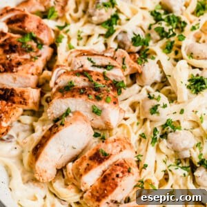 A Close-Up Shot of Sliced Chicken Breasts and Fettuccine Pasta with Alfredo Sauce