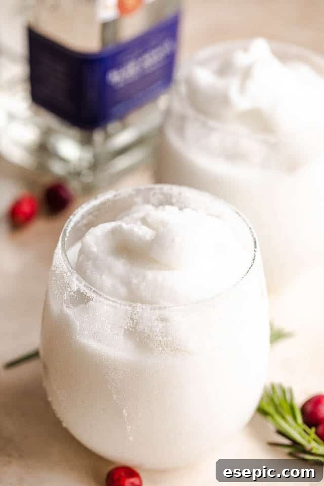 Perfectly blended frozen margaritas: a festive holiday treat. Two drinking glasses brimming with white frozen margaritas, artfully garnished with lime and cranberries, with a bottle of silver tequila subtly placed in the background.