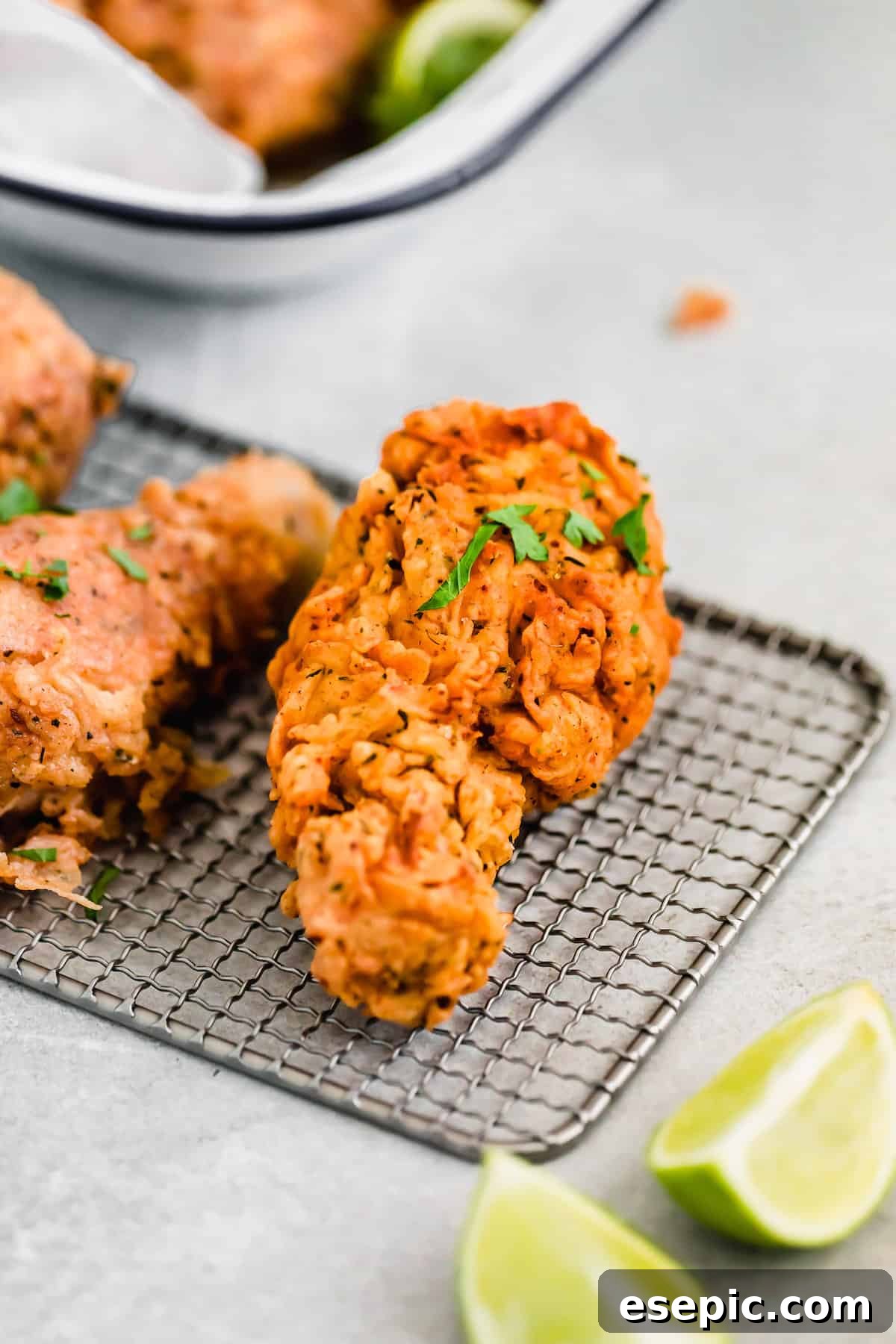 A Piece of Fried Chicken Resting Beside Two Lime Slices